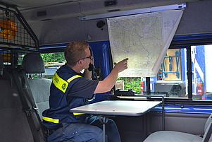 Der Zugführer prüft die Position der Einsatzkräfte auf einer Landkarte und kommuniziert per Funk.